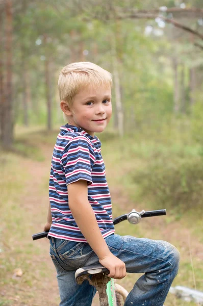 Menino em uma bicicleta vai ir em um caminho florestal — Fotografia de Stock