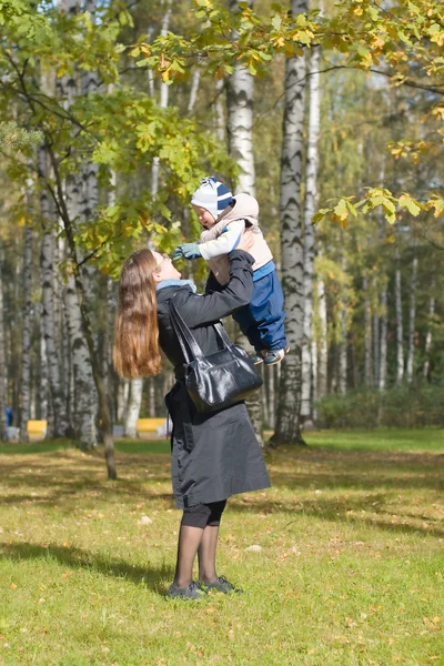 Mother holding a baby son in the autumn park — Stock Photo, Image