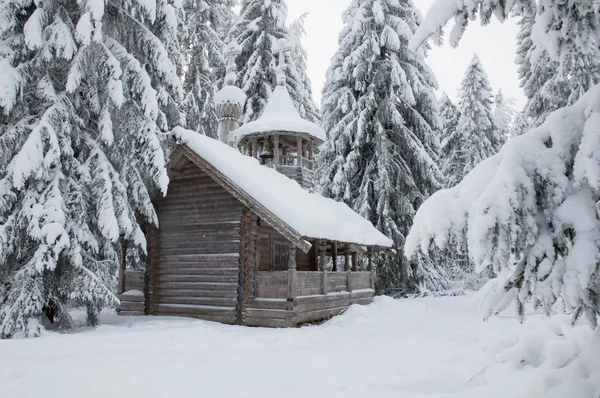 Capela de madeira em uma floresta nevada. Inverno Norte . — Fotografia de Stock