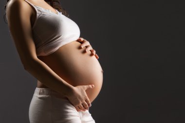 Hamile bir kadın karnını okşuyor.