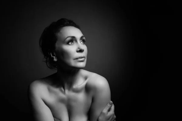 Portrait of a sensual fifty year old woman on grey studio background. Monochrome shot. — Stock Photo, Image