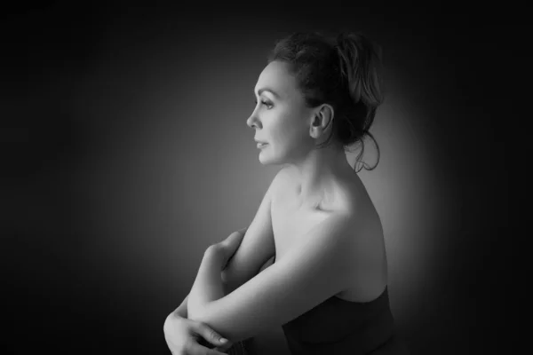 Porträtt av en sensuell femtioårig kvinna på grå studiobakgrund. Enfärgad bild. — Stockfoto