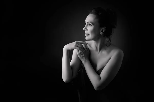 Portret van een sensuele vijftigjarige vrouw op een grijze studioachtergrond. Monochroom schot. — Stockfoto