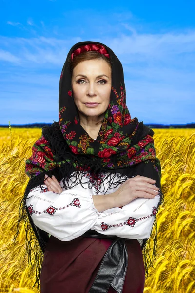 Beautiful adult ukrainian woman over yellow rape field landscape background. — Stock Photo, Image