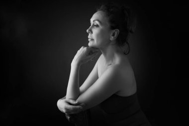 Gri stüdyo arka planında 50 yaşında şehvetli bir kadının klasik portresi. Tek renkli çekim..