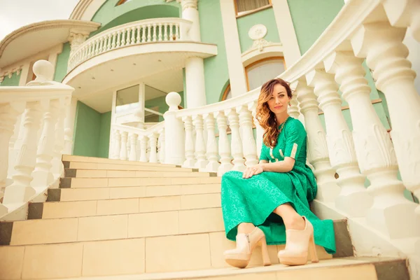 Brunet lady in green dress on stairs — Stock Photo, Image