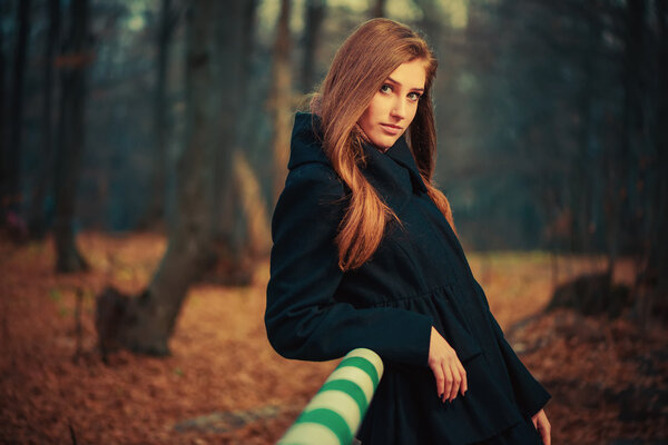 Young woman portrait in black coat at fall forest