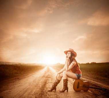 Stylish cowgirl on a sunset road