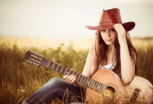 Woman with guitar at spring grass