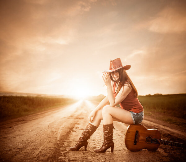 Stylish cowgirl on a sunset road