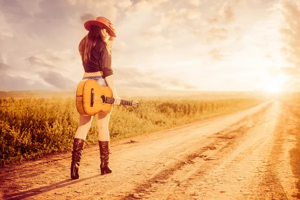 Cowgirl woth gitár egy út Stock Fotó