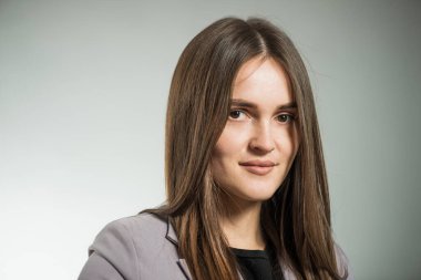 Stüdyo arka planında ofis ceketli esmer kadın portresi.