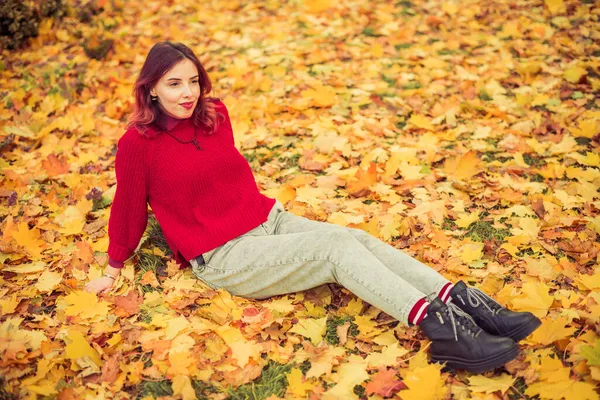 Kırmızı Kazaklı Genç Mutlu Kadın Renkli Sonbahar Yapraklarıyla Oturuyor — Stok fotoğraf