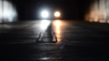 comparative characteristics of two types of headlight bulbs - led bulb vs halogen bulb simultaneously installed on the low beam of car headlights with moving car inside dark garage 