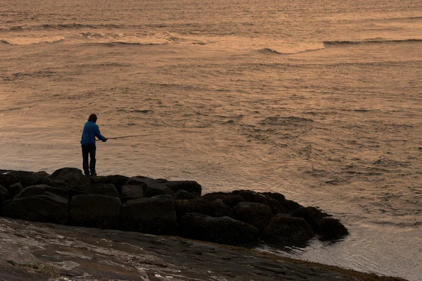 Um homem a pescar ao pôr do sol — Fotografia de Stock