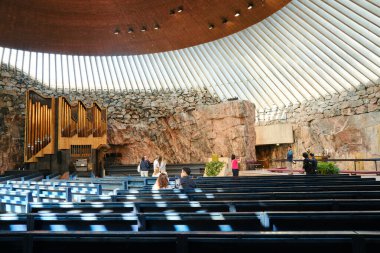 Helsinki, Finland - 10 August 2022: Interior of famous Temppeliaukio church built directly into solid rock with walking tourists in Helsinki, Finland 