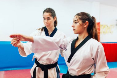 İki genç kadın bir eğitim merkezinde tekvando çalışıyor.