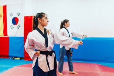 İki genç kadın bir eğitim merkezinde tekvando çalışıyor.