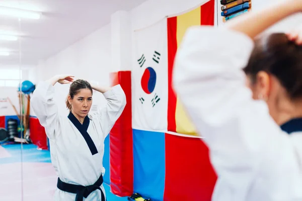 Young woman dresses in her taekwondo suit in front the mirror — Stock Photo, Image
