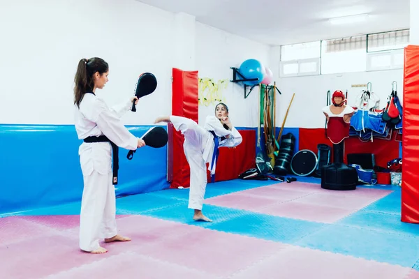 İki genç kadın bir eğitim merkezinde tekvando çalışıyor.