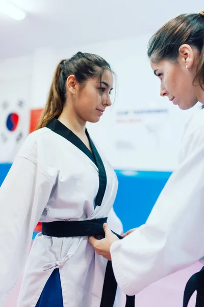 Two young women dress each other in their taekwondo kimono — Stock Photo, Image