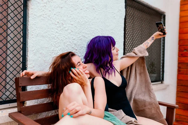 Две молодые женщины на заднем дворе летом фотографируют с помощью своих мобильных телефонов. — стоковое фото