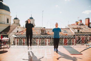 Binanın terasında egzersiz yapan, ip atlayan bir çift.