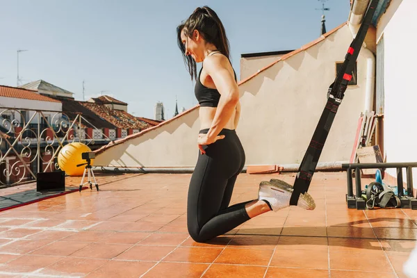 Kobieta robi trening miejski dla ramion i klatki piersiowej z trx paski fitness. Zdrowy trening na świeżym powietrzu dla siły i utraty wagi — Zdjęcie stockowe