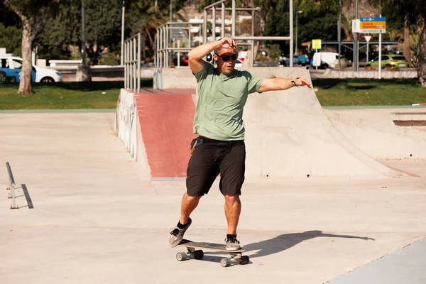 Człowiek jeżdżący na deskorolce w miejskim skateparku. Zwykły facet w spodenkach i koszulce.. — Zdjęcie stockowe