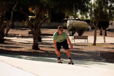 Şehir parkında kaykay yapan bir adam. Şort ve tişört giyen sıradan bir adam. Boş zaman aktivitesi, aşırı spor, şehir yaşam tarzı konsepti