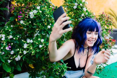 Dışarıda arka bahçede selfie çeken sevimli genç bir kadının fotoğrafı.