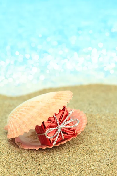 Gift box in a sea shell on the beach — Stock Photo, Image
