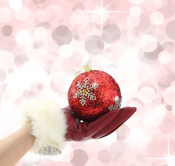 Woman's hand with red glove holding a Christmas ball — Stock Photo, Image