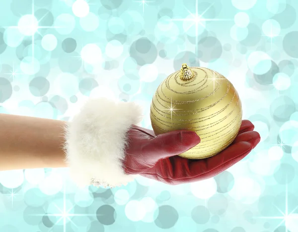 Main de femme avec un gant rouge tenant une boule de Noël — Photo