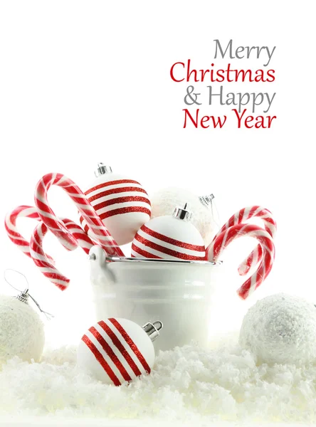 Kerstballen en snoepjes in een cup op sneeuw — Stockfoto