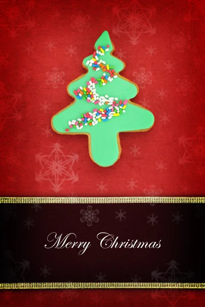 Biglietto natalizio con biscotto ad albero su sfondo rosso — Foto Stock