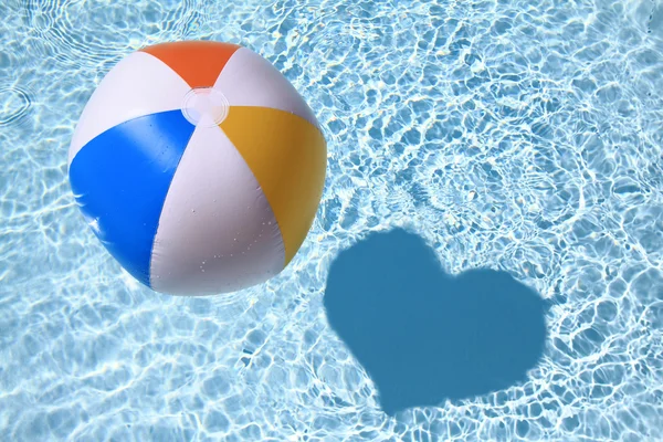 Amour d'été, Balle de plage sur la piscine avec ombre en forme de coeur — Photo