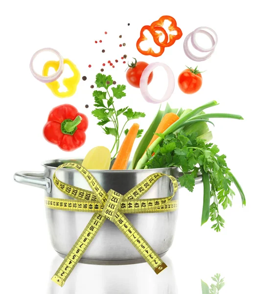 Fresh vegetables falling into a casserole pot with measuring tape — Stock Photo, Image