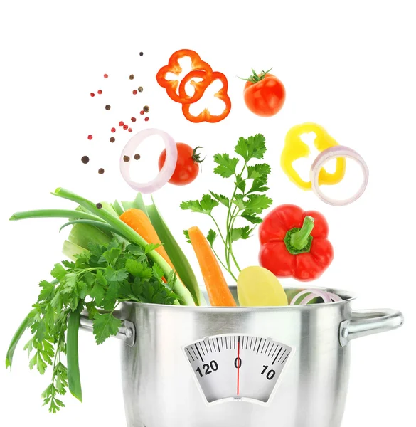 Fresh vegetables falling into a casserole pot with weight scale — Stock Photo, Image