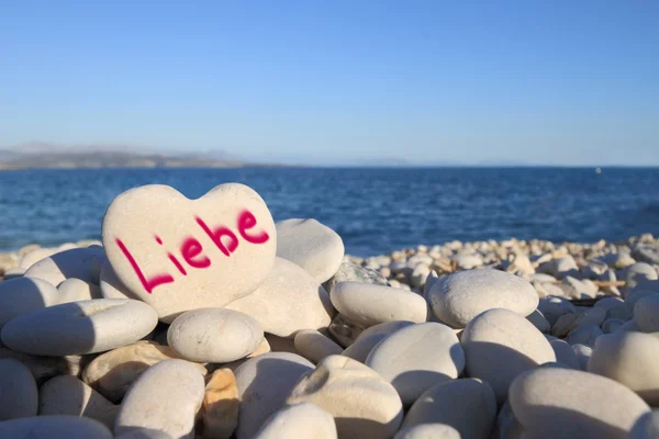 Liebe written on heart shaped stone on the beach — Stock Photo, Image