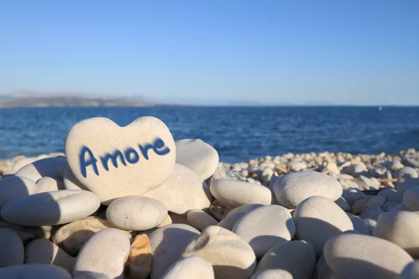 Amore skriven på hjärtformade sten på stranden Royaltyfria Stockbilder