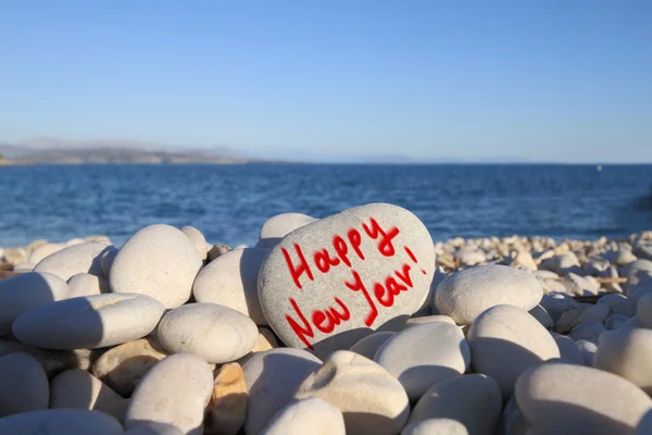 Bonne année écrite sur pierre en forme de coeur sur la plage avec brosse à pulvériser — Photo