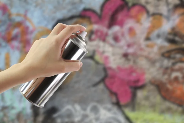 Ανθρώπινο χέρι κρατώντας ένα γκράφιτι σπρέι μπορεί μπροστά από ένα πολύχρωμο τοίχο — Φωτογραφία Αρχείου
