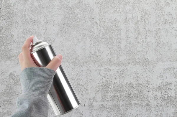 Mano humana sosteniendo una lata de graffiti Spray frente a una pared de hormigón en blanco — Foto de Stock