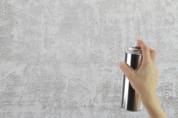 Human hand holding a graffiti Spray can in front of blank concrete wall — Stock Photo, Image