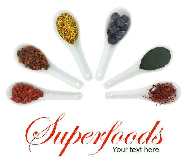 Superfoods dans des cuillères en porcelaine. Pollen, baies de goji, bleuets, spiruline, hippophae et safran — Photo