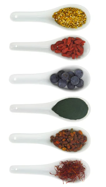 Superfoods en cucharas de porcelana. Polen, bayas de goji, arándanos, espirulina, hipofa y azafrán —  Fotos de Stock