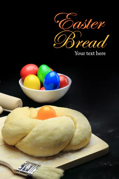 Easter sweet bread dough with multicolored eggs on black background — Stock Photo, Image