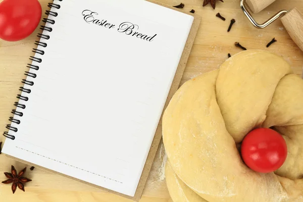 Paskalya tatlı ekmek hamuru ile masada kırmızı yumurta ve tarif kitabı — Stok fotoğraf