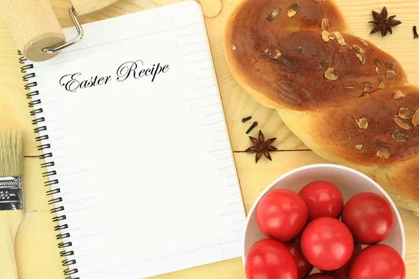 Słodki chleb Wielkanoc z czerwonych jaj i książkę kucharską na stole — Zdjęcie stockowe
